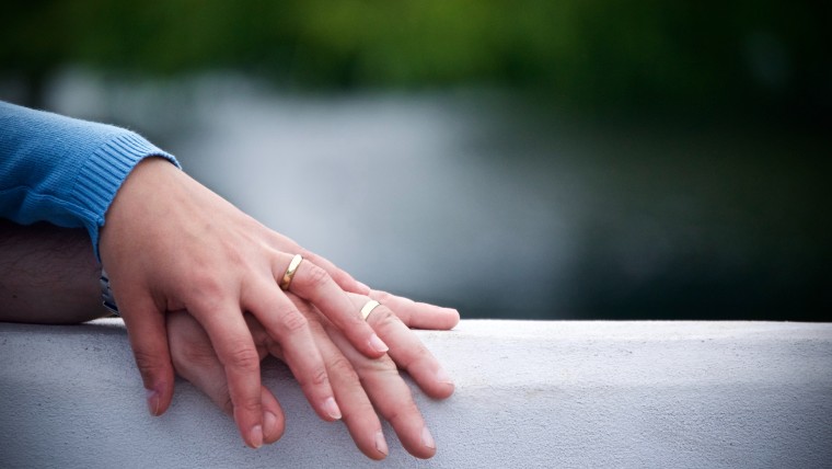 two hands with wedding bands intertwined.