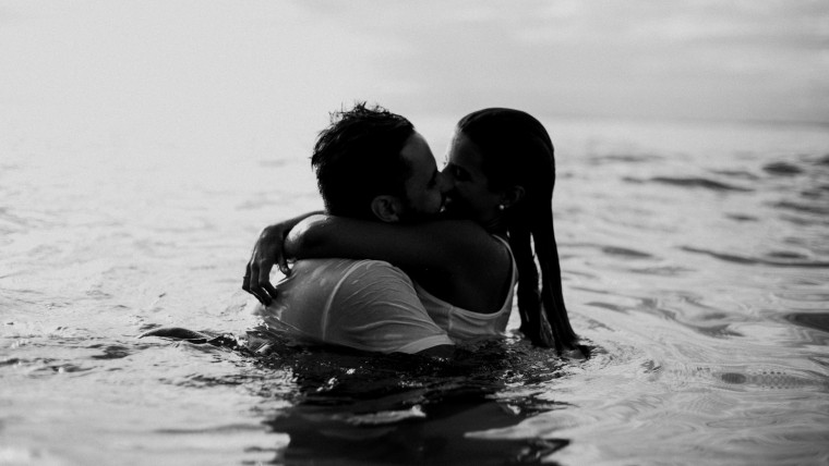 man and woman kissing in the water